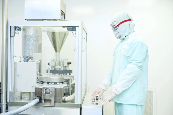 Trabajador que opera la máquina de llenado de cápsulas farmacéuticas —  Fotos de Stock