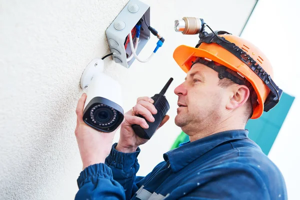 Technician worker installing video surveillance camera on wall