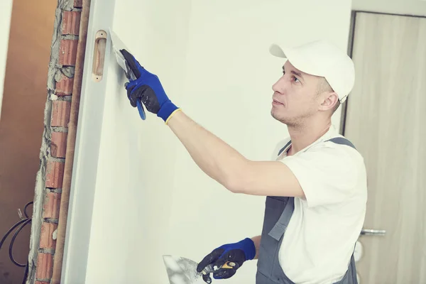 Sanierung. Arbeiter bearbeiten eine Wand mit Spachtel — Stockfoto