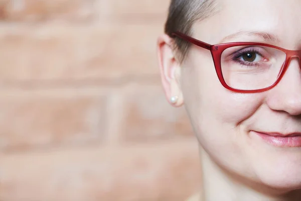 Half face portrait of young smiling woman in glasses — Stock Photo, Image