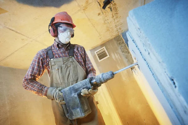 breaking interior wall. worker with demolition hammer