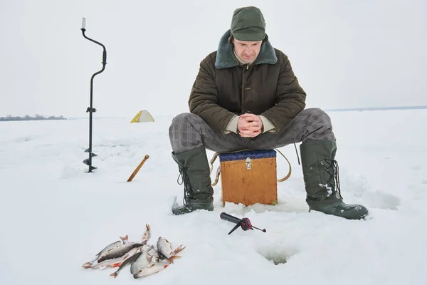 Рыбалка зимой. Рыбак ждет укус рыбы — стоковое фото