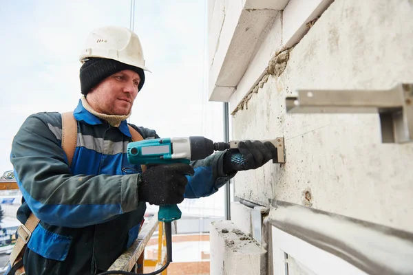 Bauarbeiter montiert Halterung an Hausfassadenwand — Stockfoto