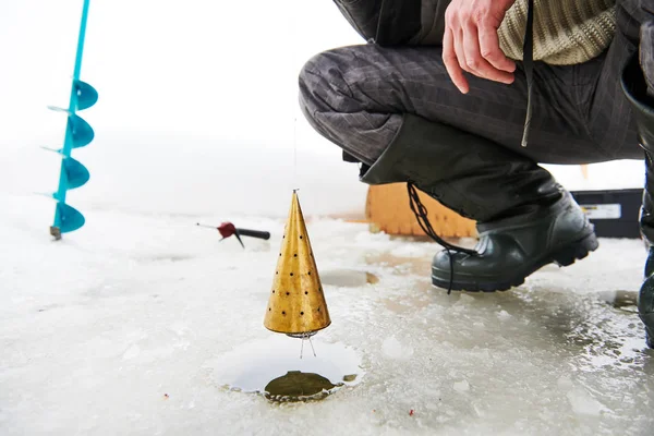 Pêche en hiver. Pêcheur nourrissant et attirant les poissons avec mangeoire — Photo