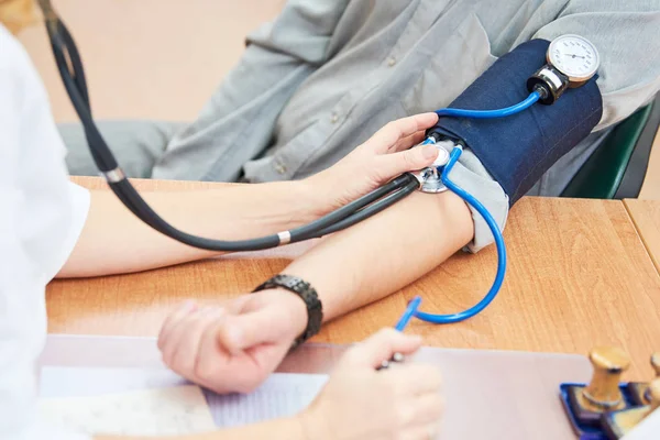 Physician doctor is checking the blood pressure of the patient — Stock Photo, Image