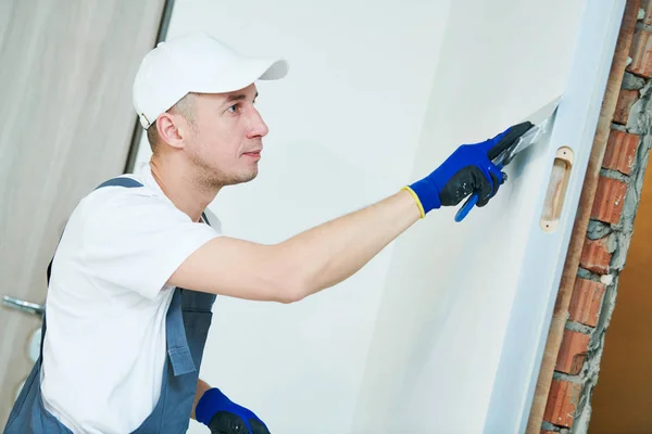 Opknappen. Werknemer spackling een muur met stopverf — Stockfoto