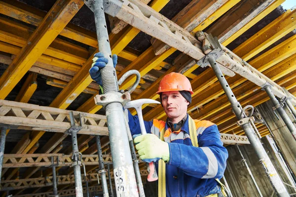 Constructor que instala o desmonta el soporte de poste para encofrado monolítico de hormigón en la construcción de viviendas — Foto de Stock