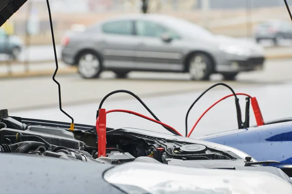 Ayuda automovilística. cables de puente de refuerzo cargando la batería descargada del automóvil —  Fotos de Stock