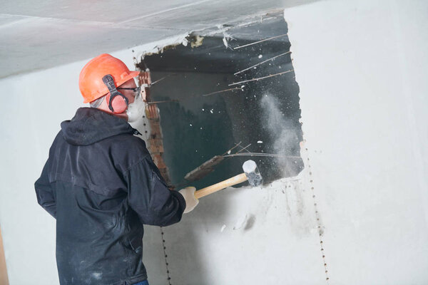demolition work and rearrangement. worker with sledgehammer destroying wall