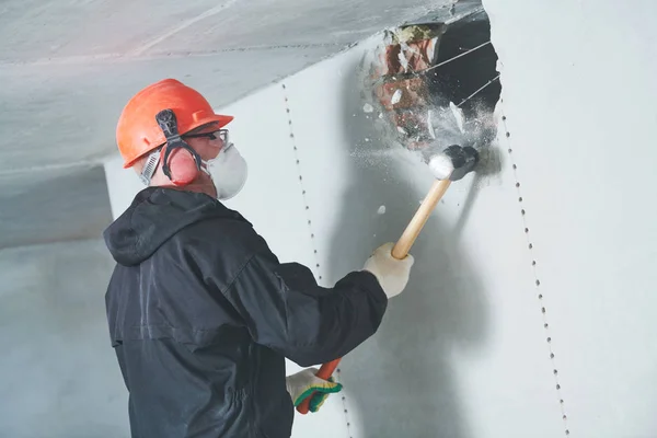 Trabajos de demolición y reordenamiento. trabajador con martillo de trineo destruyendo la pared Fotos De Stock