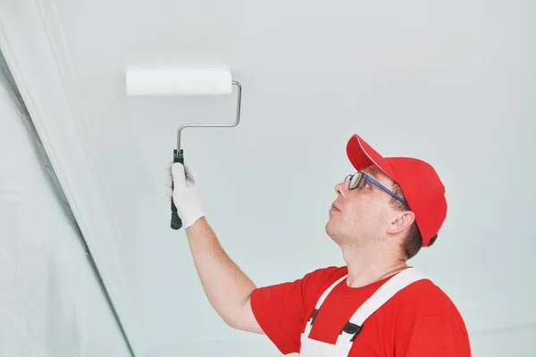 Painter worker with roller painting ceiling surface into white — Stock Photo, Image