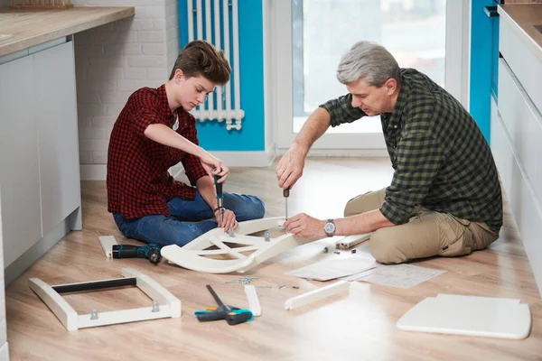 Vader en zoon werken samen. keukenstoel monteren — Stockfoto