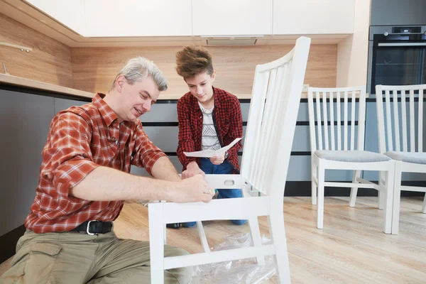 Padre e hijo trabajan juntos. montaje de silla de cocina — Foto de Stock