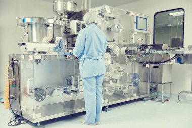 Eczacılık. İlaç işçisi su toplayan ambalaj makinesi kullanıyor.