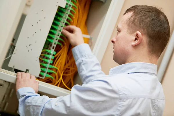 Elettricista lavora con cavi in fibra ottica nel quadro elettrico — Foto Stock