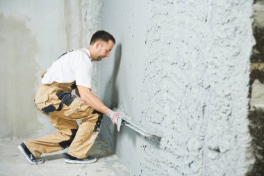 Plasterer using screeder smoothing putty plaster mortar on wall clipart