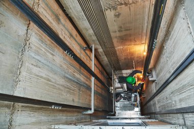 lift machinist repairing elevator in lift shaft clipart