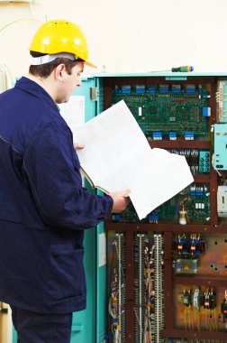 Elektrik mühendisi mühendisi asansör anahtarı tahtasındaki elektroniği test ediyor.