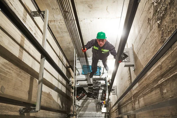 Lift machinist repairing elevator in lift shaft — Stock Photo, Image