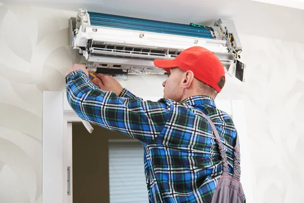 Air conditioner service. Worker at climatization system installation indoors