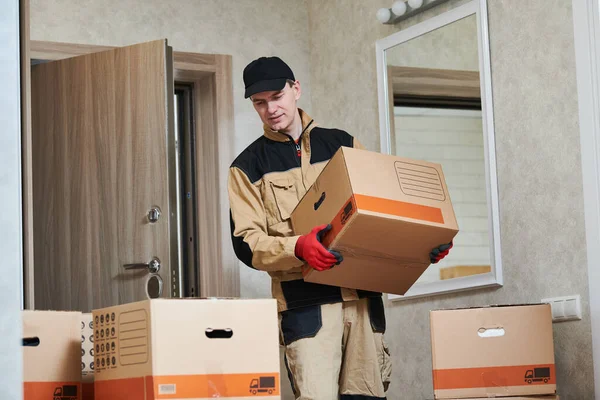 Moving or delivery service. Worker carrying cardboard boxes into home
