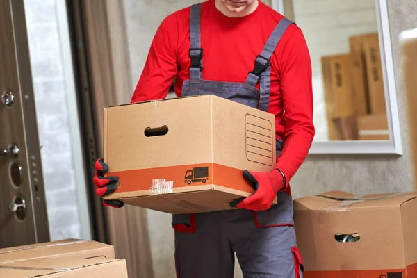 Moving or delivery service. Worker carrying cardboard boxes into home