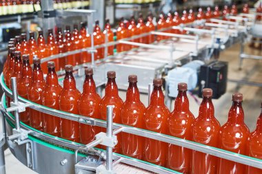 Biralı plastik şişeler ya da konveyörde hareket eden karbonatlı içecek.