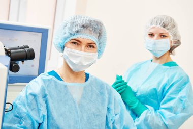 Optalmolojik ameliyathanede asistanı olan kadın cerrah.