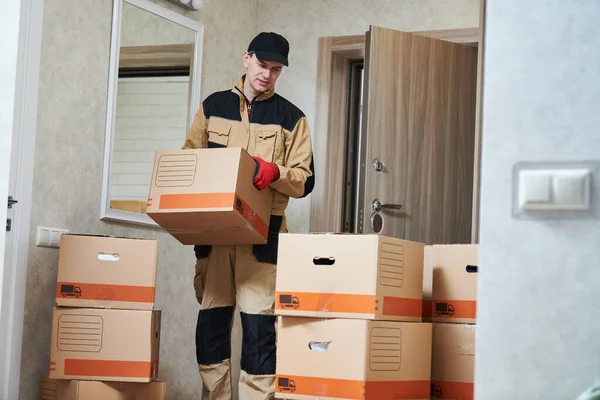 Moving or delivery service. Worker carrying cardboard boxes into home — Stock Photo, Image