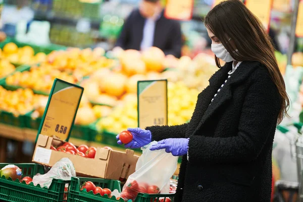 Mujer con máscara y guantes protectores comprando comida en tienda en coronavirus epidemia —  Fotos de Stock