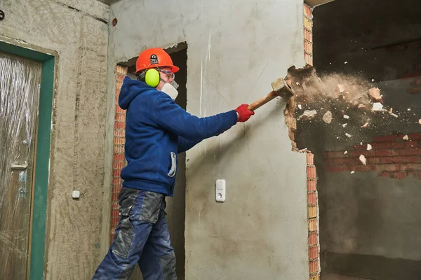 Abrissarbeiten und Umgestaltung. Arbeiter mit Vorschlaghammer zerstört Mauer — Stockfoto