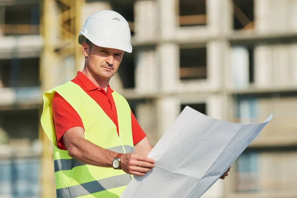 Construction worker with blueprint at building area — Stock Photo, Image