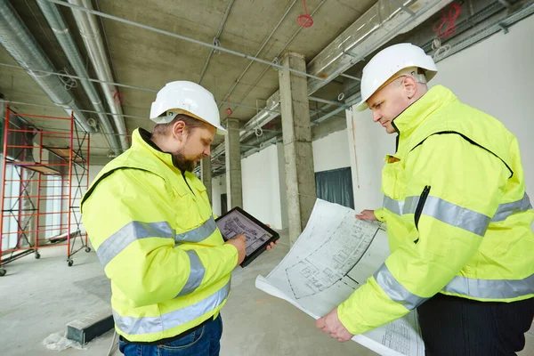 Two building engineers with project at construction site — Stock Photo, Image