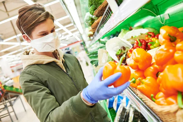 Mann mit Maske und Schutzhandschuhen kauft bei Coronavirus-Epidemie Lebensmittel im Geschäft — Stockfoto