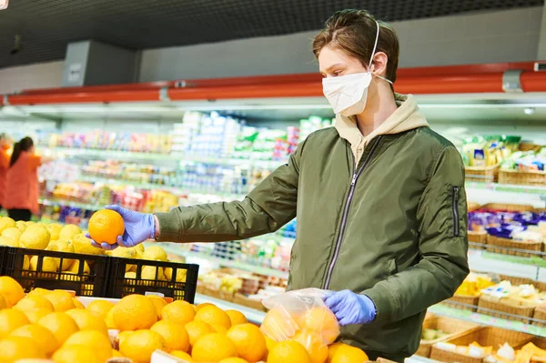 Uomo in maschera e guanti protettivi acquisto di cibo in negozio a coronavirus epidemia — Foto Stock