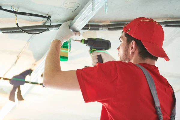 Gips gipsplaten. Drywall constructie thuis. Werknemer die metalen frame aan het plafond installeert — Stockfoto