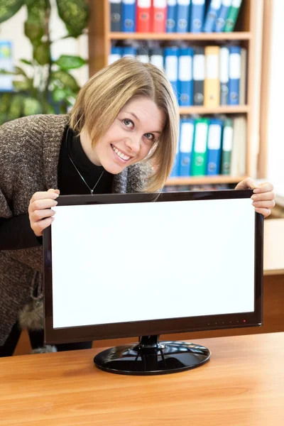 迷人而快乐的女人拿着Pc监视器 带着空白的白色显示器 一个办公室的内部 — 图库照片