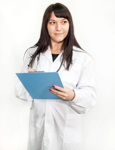 白い背景 白いコート 青いクリップボードに彼女の手の上に立って仕事で医師の女性 — ストック写真