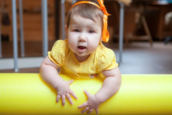 小さな女の子の肖像画 赤ちゃんは国内のジムで黄色の泡ローラーに横たわって カメラを見て — ストック写真