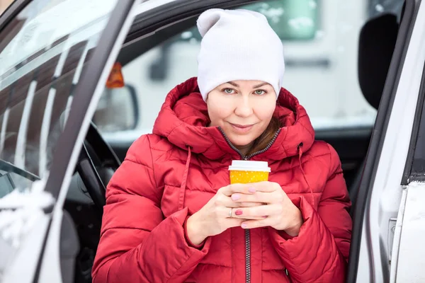 漂亮的中年妇女 手里拿着装有热咖啡的纸杯 坐在开着车门的车里 — 图库照片