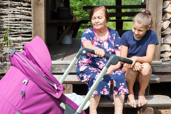 Senior Grootmoeder Zwaait Een Kinderwagen Met Baby Tiener Leeftijd Meisje — Stockfoto