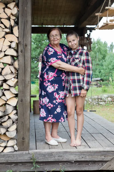 Äldre Mormor Omfamnar Sitt Tonåriga Barnbarn Står Tak Trä Veranda — Stockfoto