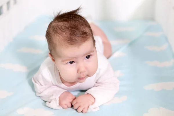 2ヶ月のベビーベッドの上の胃 青い底と白いリネン 1人の幼児 — ストック写真