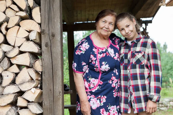 Portrét Postarší Babičky Svou Vnučkou Stojící Pod Střechou Dřevěného Domku Stock Snímky