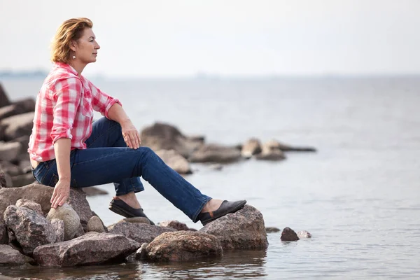 Mujer Caucásica Sentada Piedra Cerca Del Agua Contempla Océano Gris —  Fotos de Stock