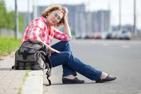 白人妇女搭便车 一个人坐在路边等车 — 图库照片