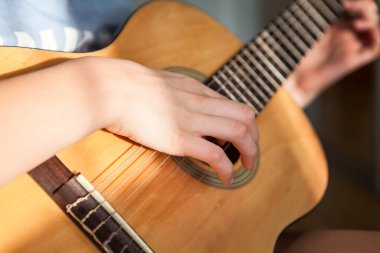 Dişi eller, sarı akustik gitarın tellerini ve fretboard 'unu koparır.