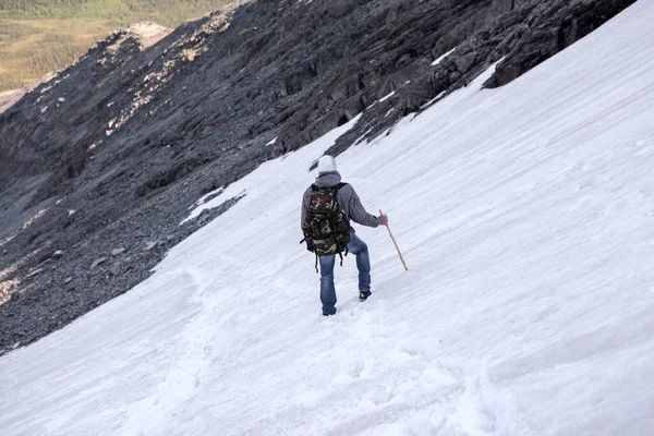 ハイカーは山を下り 棒で雪の急な坂を歩き 谷に降ります — ストック写真