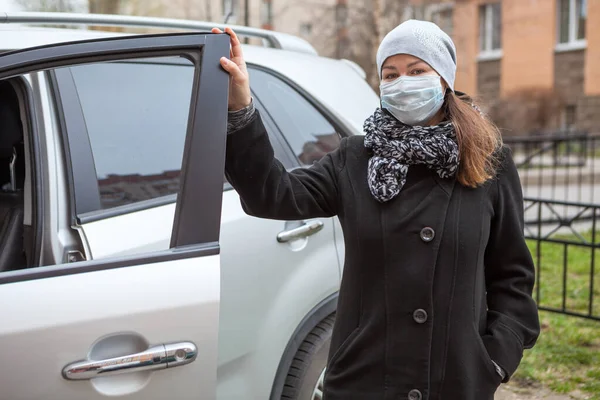 黒コートと顔マスクを身に着けている白人女性立ち隣に彼女の車とともにオープンドア — ストック写真