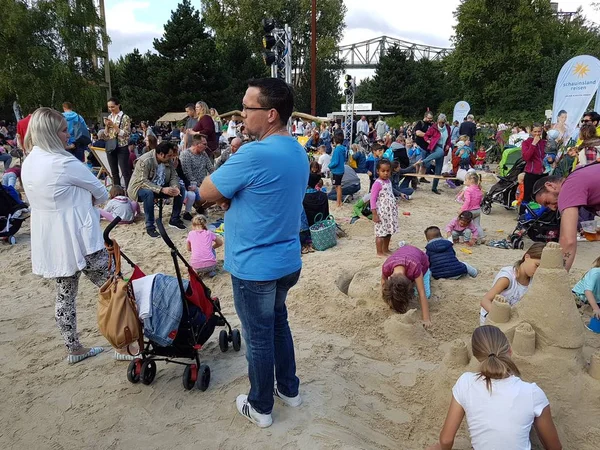 Ebeveynler ve kumla oynayan çocuklar